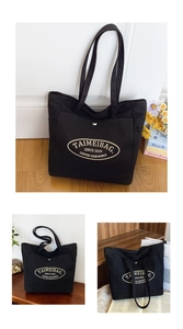 Detail of black canvas tote bag showing the front button pocket and printed logo