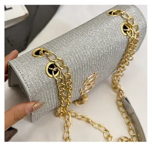 Detail of silver glitter crossbody bag with gold chain strap and metal logo hardware