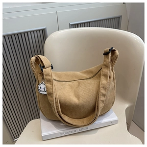 Détail du sac fourre-tout en velours côtelé marron clair avec pendentif chiot blanc sur chaise