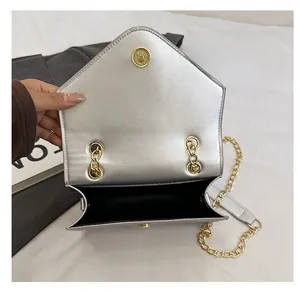 Silver metallic crossbody bag showing internal black compartment and magnetic snap closure