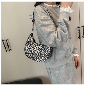 Detailed side view of leopard print crescent bag on a model showing sleek curve and texture