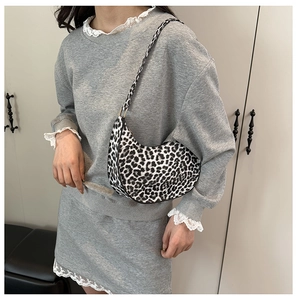 Detail of leopard print crescent bag showing the gold metal buckle and shoulder strap fit