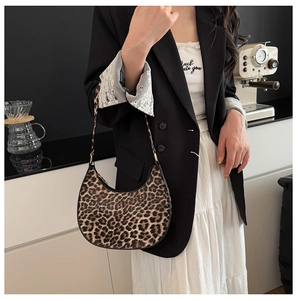 Close-up of leopard print crescent hobo bag with sleek curved silhouette and slim strap