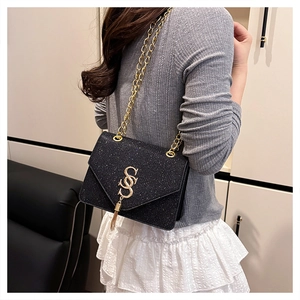 Détail d'un sac bandoulière noir à paillettes avec chaîne dorée et pendentif à gland