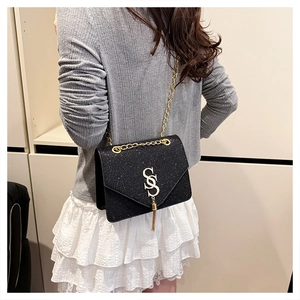 Détail du sac bandoulière à paillettes noires avec chaîne dorée et gland logo S