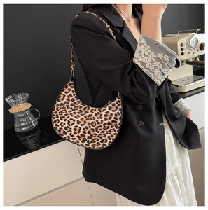 Close-up of leopard print crescent bag with plush texture and slim black shoulder strap