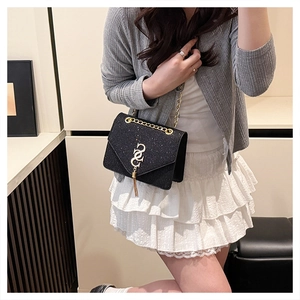 Détail du sac bandoulière noir pailleté avec pompon doré et boucle en métal chic