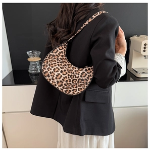 Detail of leopard print crescent bag showing animal texture and curved shoulder strap