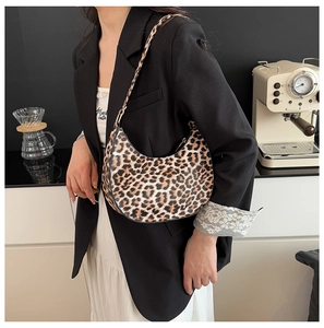 Chic leopard print crescent bag styled as an underarm shoulder bag on a model
