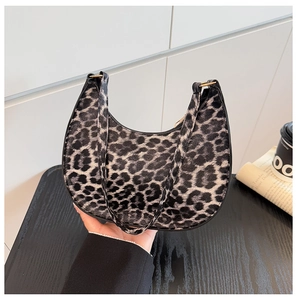 Detailed close-up of leopard print crescent bag with golden metal rings and fine strap