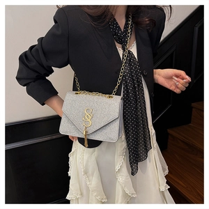 Gros plan d'un sac à main argenté à paillettes avec chaîne dorée porté par un mannequin