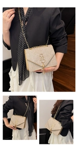 Détail du sac bandoulière à paillettes dorées avec logo S en métal, franges et chaîne chic