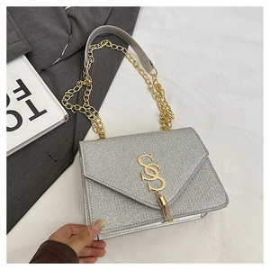 Détails du sac à main argenté à paillettes avec logo doré et pompon décoratif chic