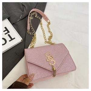Détail du sac rose avec fermoir en S doré, breloque pompon et bandoulière chaîne