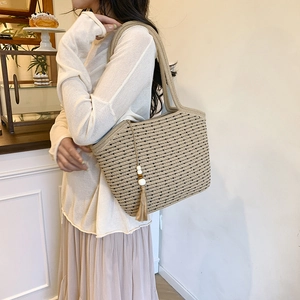 Handwoven straw tote bag with black polka dots and tassels for summer beach vacation