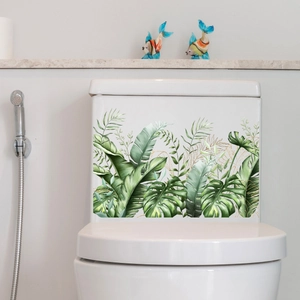Detailed view of self-adhesive tropical leaf decals with gold edges on toilet tank