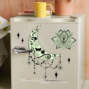Glow in the dark moon and lotus wall stickers on a retro cream fridge in a warm room