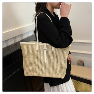 Straw tote bag detail with white leather trim shown on shoulder in a lifestyle setting