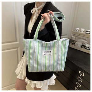 Vertical striped canvas tote bag in purple, green, and white colors with fashion label