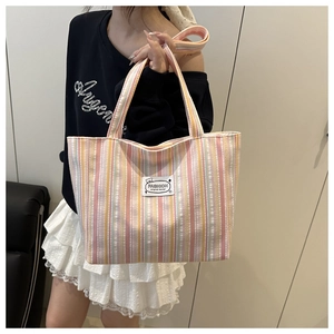 Detailed shot of striped canvas tote bag with pink and yellow pleats and fashion patch