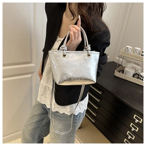 Close-up of metallic silver bucket bag with embossed text and soft handle detail