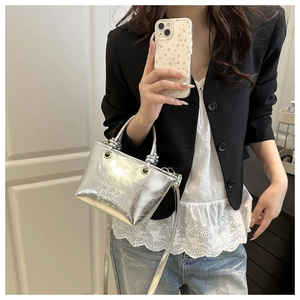 Silver metallic bucket bag with ring handle shown in a stylish crossbody wear photo