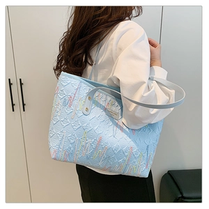 Detail shot of blue striped tote bag with embossed textures and wavy embroidery patterns