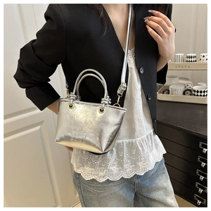 Detail showing metallic silver bucket bag with embossed logo and knotted handle decor