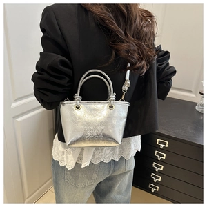 Detail of silver metallic bucket bag with embossed letters and cracked leather texture