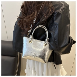 Silver metallic tote bag with embossed text and glossy pleated texture on model
