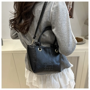 Detail of black cracked leather bucket bag with embossed logo and golden hardware