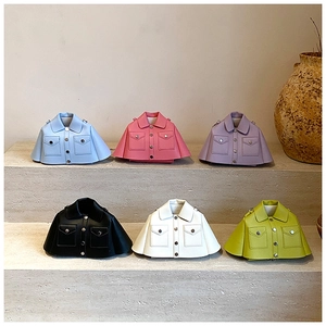 Mini jacket-shaped crossbody bags in pastel colors displayed on stone steps