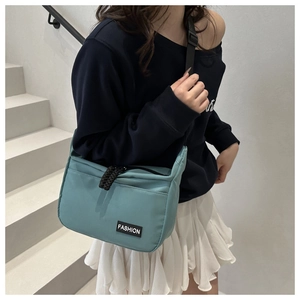 Detailed close-up of light blue canvas crossbody bag with Fashion logo and black strap