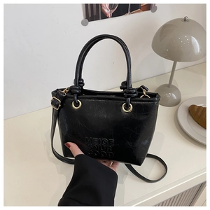 Detail of black cracked leather texture and embossed lettering on a chic bucket bag