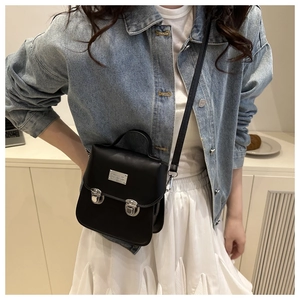 Vista indossata di una mini borsa a tracolla nera con fibbie argento e manico superiore