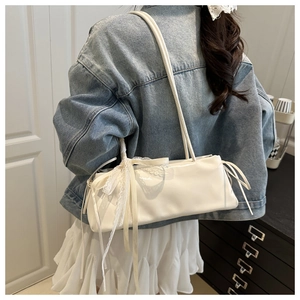Close-up of white baguette bag with lace ribbon bow detail styled with casual outfit