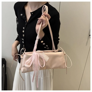 Detail of pink oil wax leather baguette bag with lace trim and satin bow detail