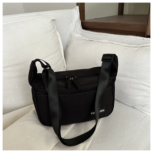 Detail of black canvas crossbody bag with dual zipper and FASHION woven label
