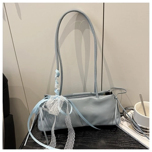 Detail of light blue oil wax leather bag with lace ruffles and ribbon bow decoration