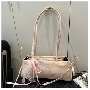 Detail of pink shoulder bag featuring lace bow decoration and premium leather texture