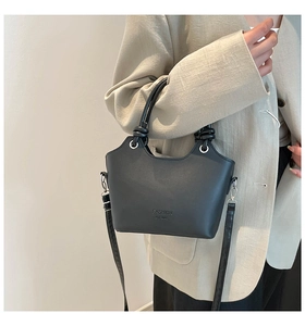 Detail of black matte PU leather bucket bag with top handle and fashion logo lettering