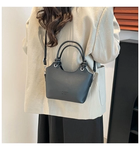 Detail of black matte leather bucket bag featuring round handles and silver hardware