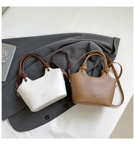 Detailed close-up of knotted handles on white and caramel brown fashion handbags