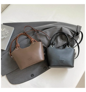 Detail of trendy bucket bags in black and brown PU leather with knotted handle design