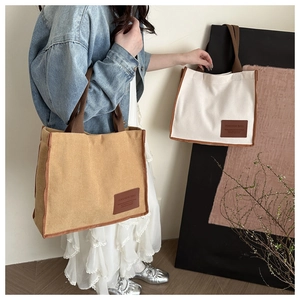 Detail of khaki corduroy tote bag featuring brown woven straps and leather fashion label
