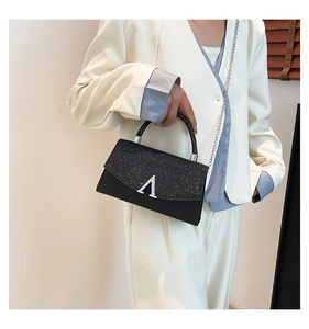 Sac de soirée noir à paillettes avec fermoir en V argenté porté en bandoulière par un mannequin