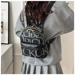 Detail of a vintage-style letter print backpack with gold studs and adjustable straps