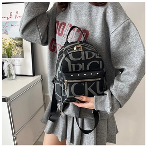 Detail of vintage black backpack with letter print, front zip pocket and gold metal rivets