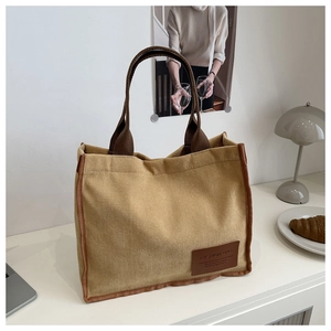 Detail of corduroy tote bag showing ribbed texture and brown woven straps in a cozy setting