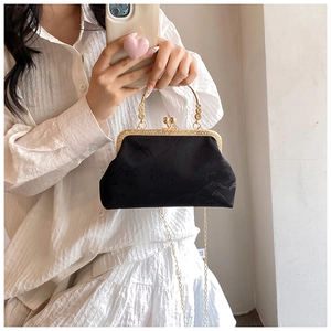 Detail of vintage black embroidered handbag with intricate gold floral metal handles